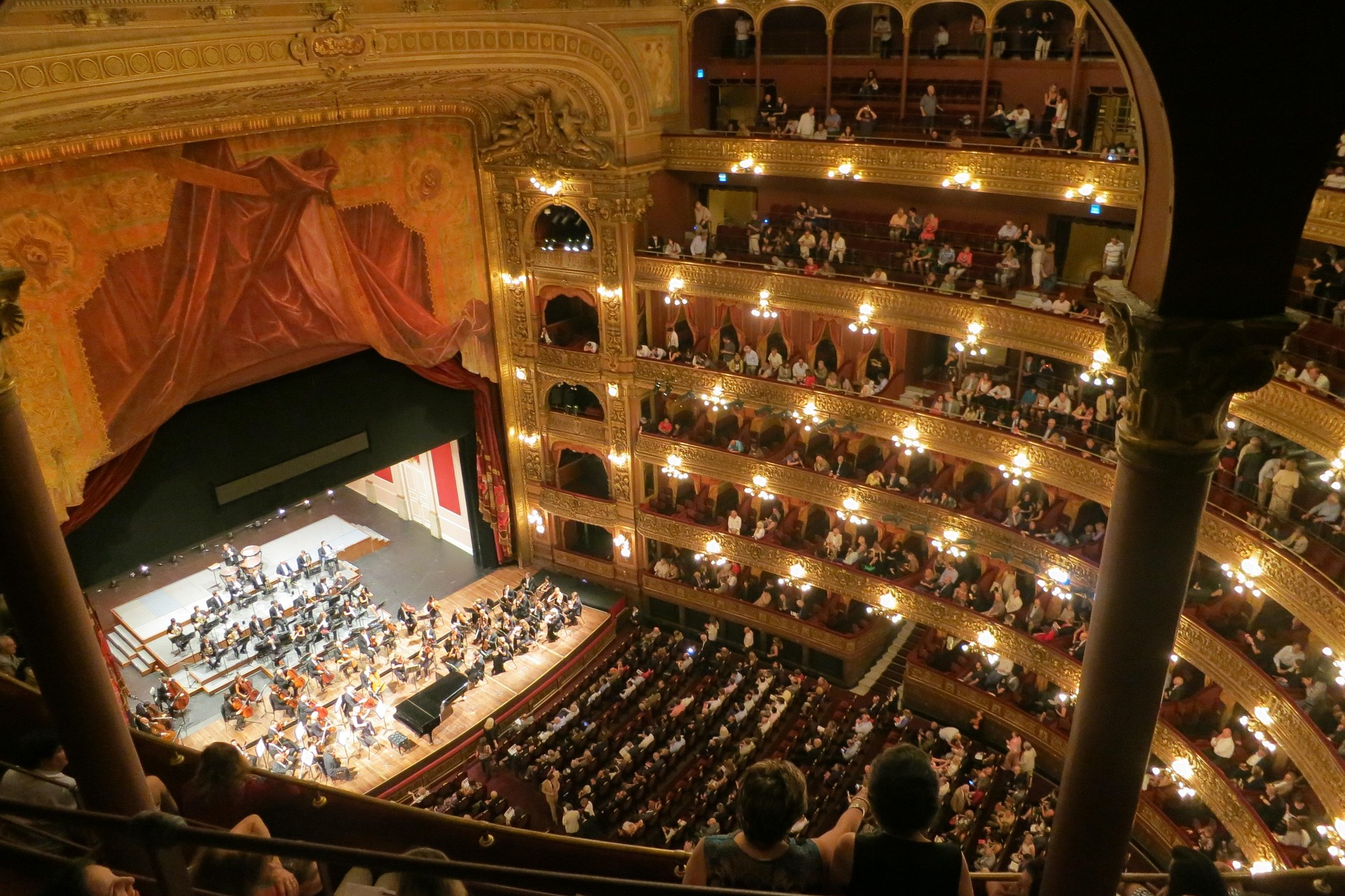 Teatro dell’opera con orchestra sul palco e pubblico nei palchi e in platea